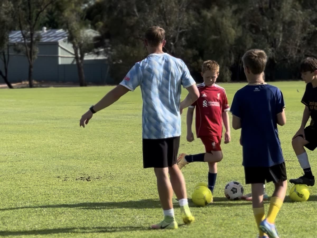 Riley coaching a small group of players with footballs